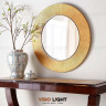 Круглое зеркало в золотой раме “LIGHED” рядом с вазой